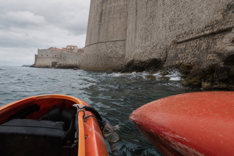 Seen low from a kayak bobbing on the Adriatic, Dubrovnik's great limestone sea wall towers overhead, waves slapping the base