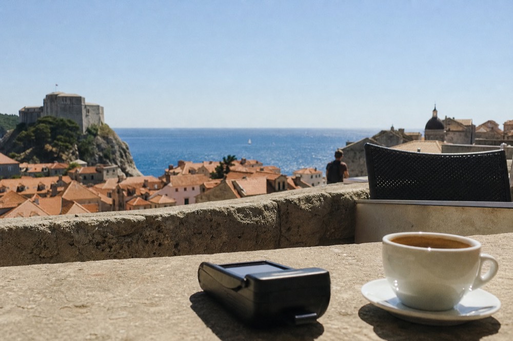 A card reader on a cafe counter beside a coffee cup on a stone terrace
