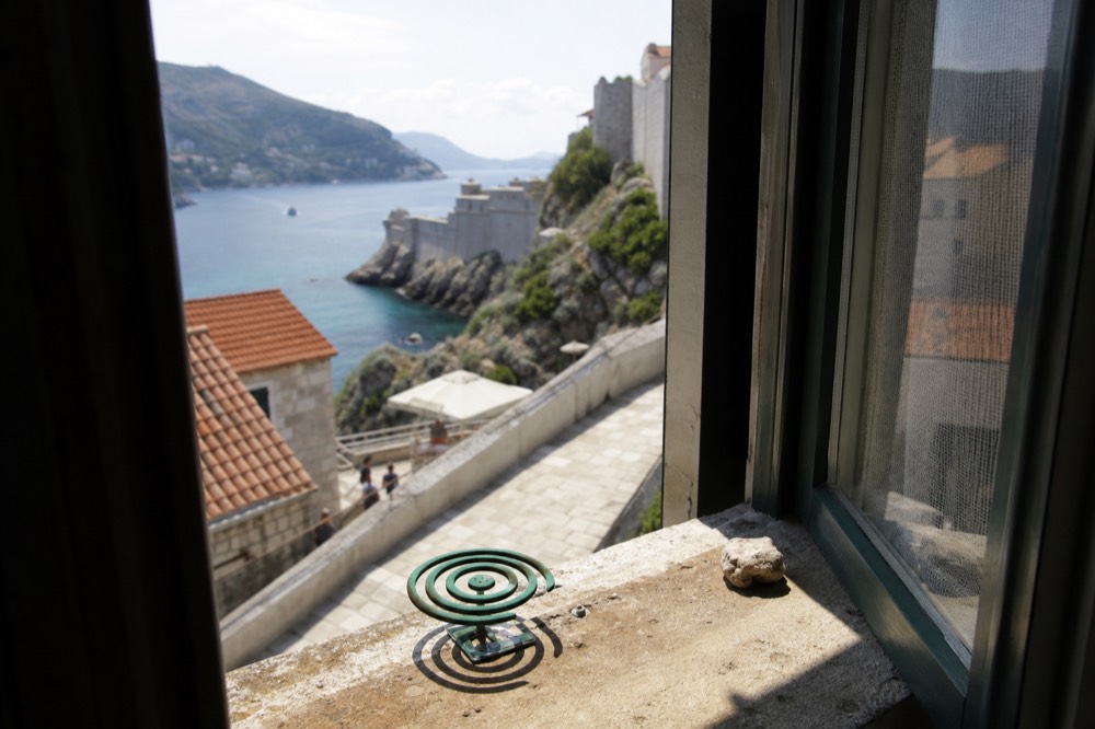 Mosquito coil burning on a stone windowsill with the Adriatic coastline in the background