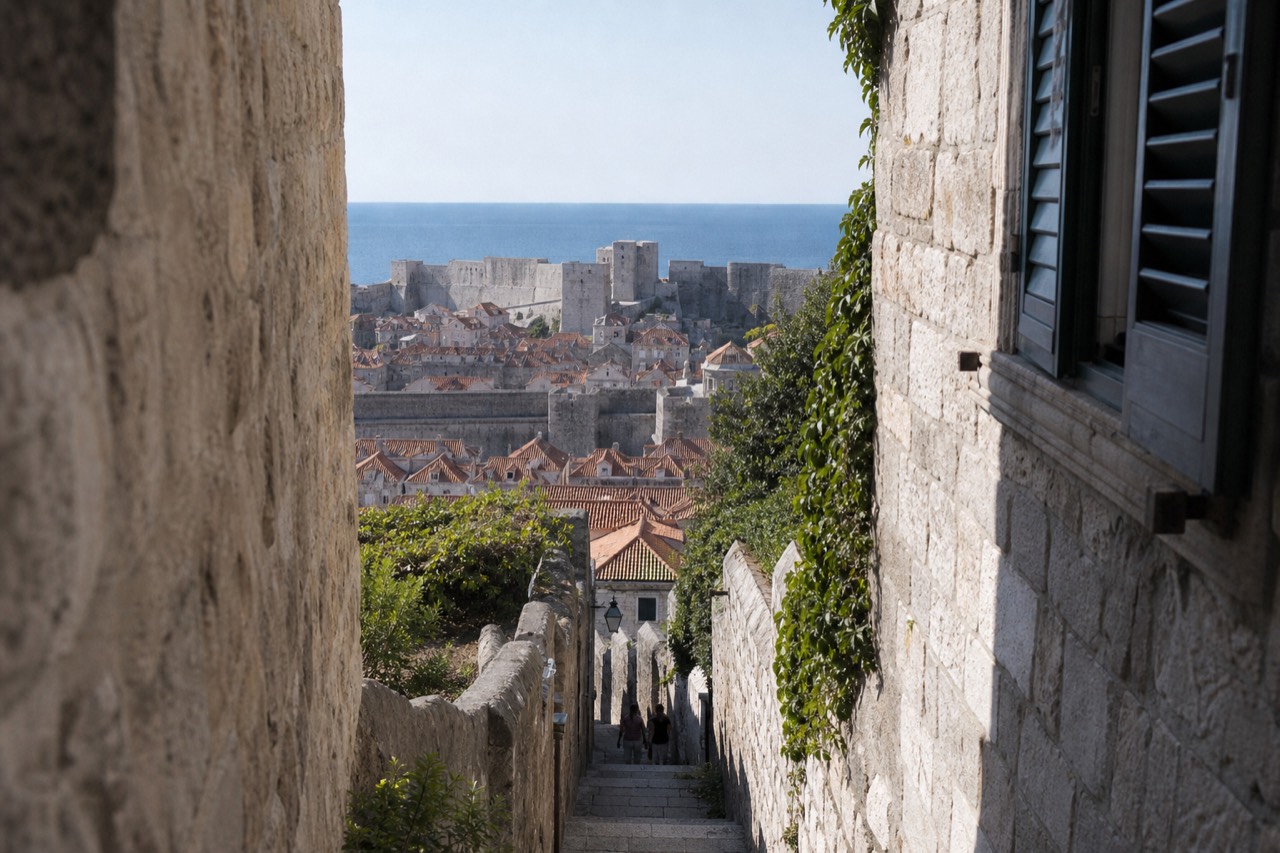 The stone city walls of Dubrovnik rising above red rooftops toward the Adriatic sea