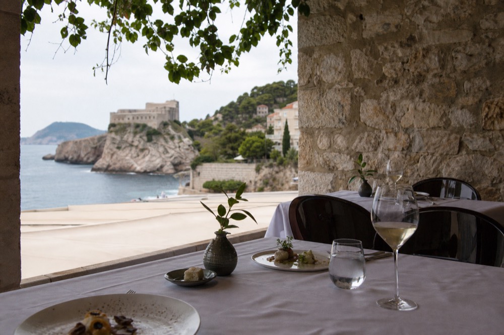 A white-tablecloth restaurant interior with bare stone walls and small plated courses