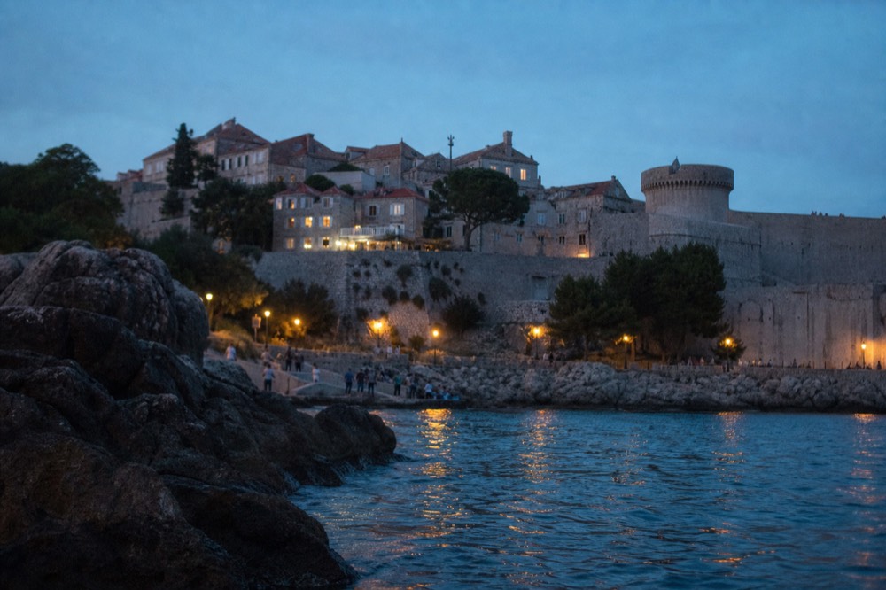 The stone walls and a round tower of Dubrovnik Old Town seen from above with terracotta rooftops