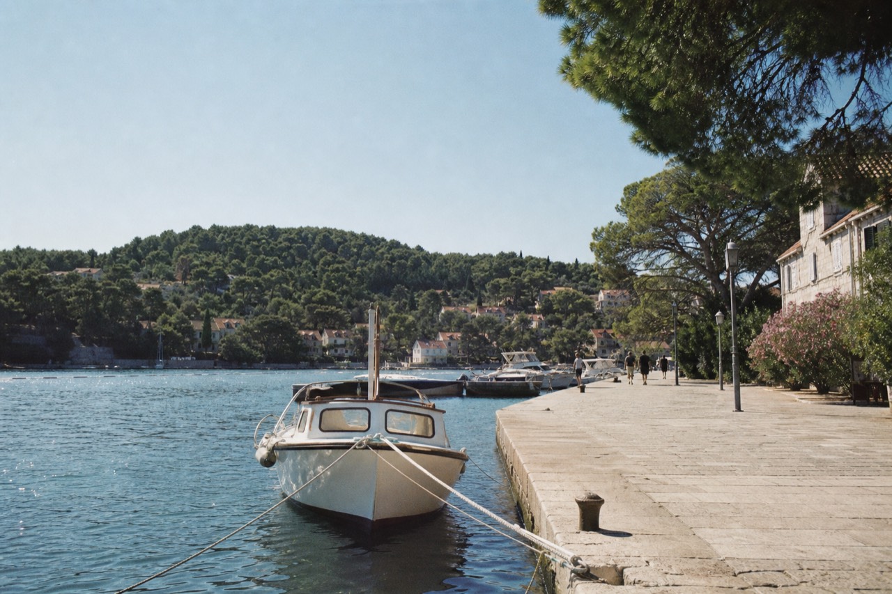 A small boat moored in a sheltered harbour with wooded hills behind it