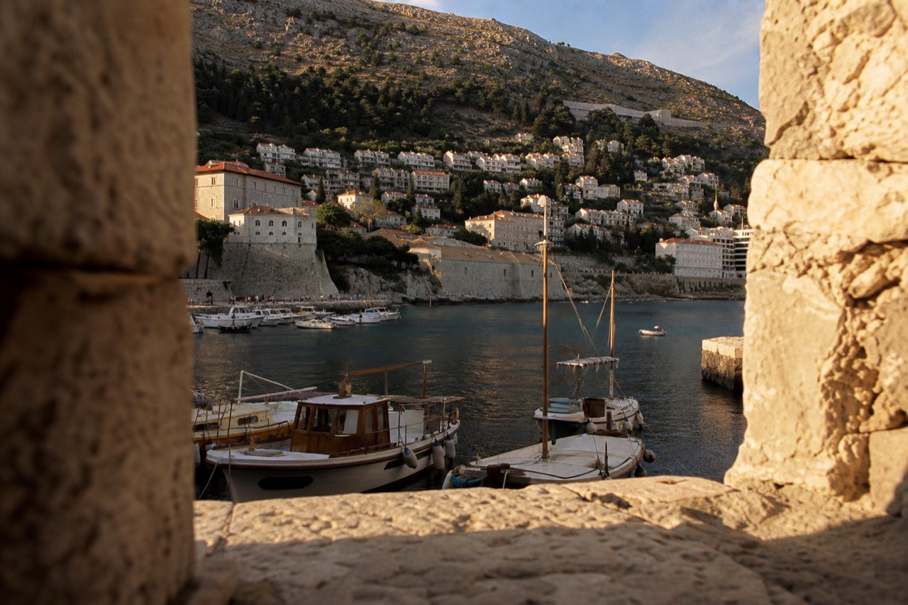 Wooden boats moored in a sheltered Adriatic bay with stone hills rising behind them