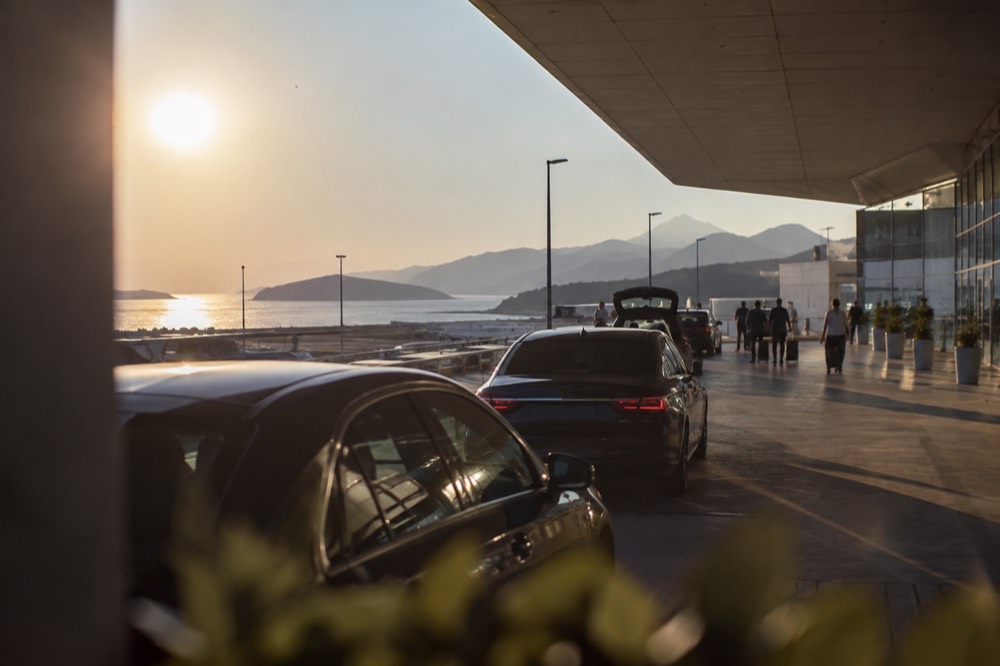 A taxi rank beside Dubrovnik Airport terminal with cars waiting in late afternoon light