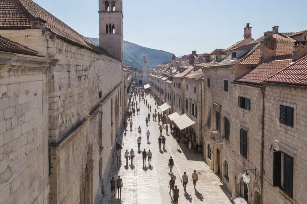 The limestone Stradun street in Dubrovnik glowing under strong midday sun with long shadows