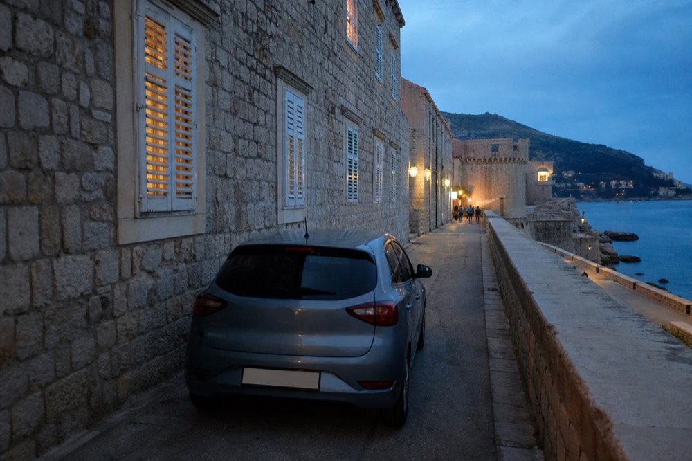 A rental car parked on a narrow street outside the stone walls of Dubrovnik