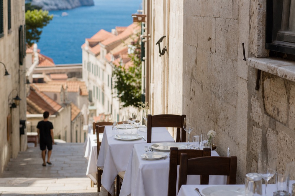 Restaurant tables with white cloths set along a narrow stone street in Dubrovnik