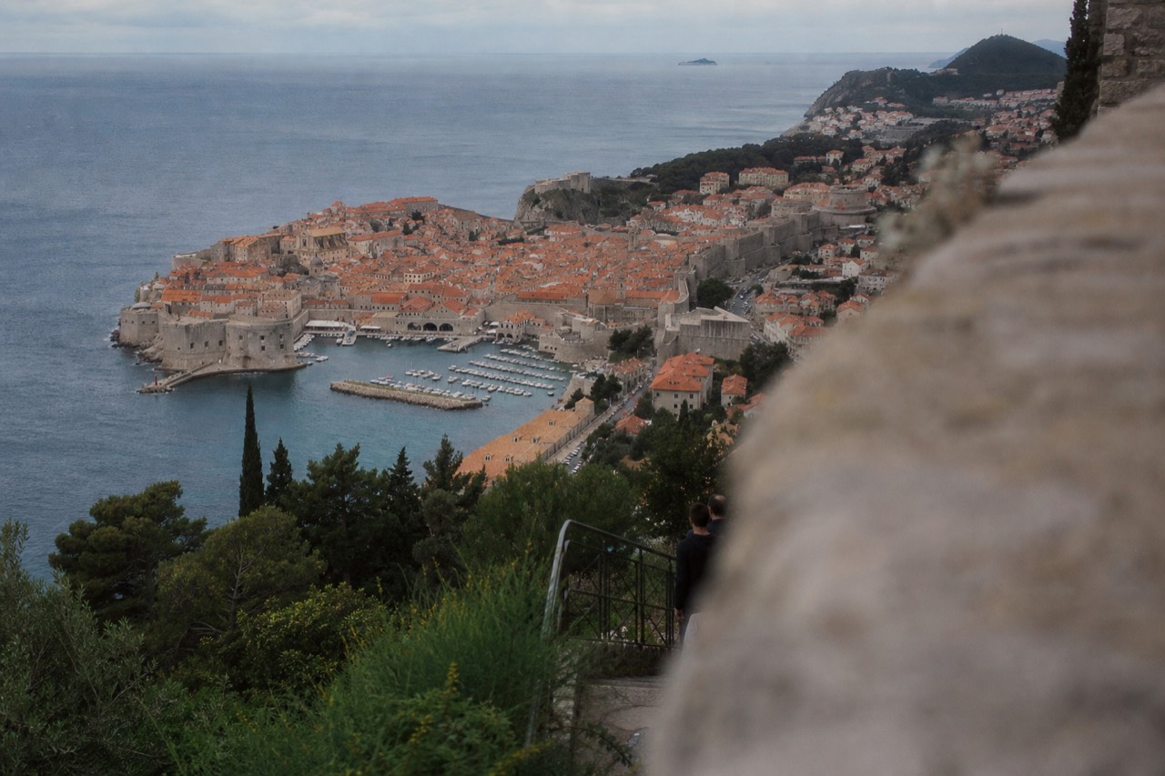 The walled Old Town of Dubrovnik seen from above with terracotta rooftops and the Adriatic sea beyond