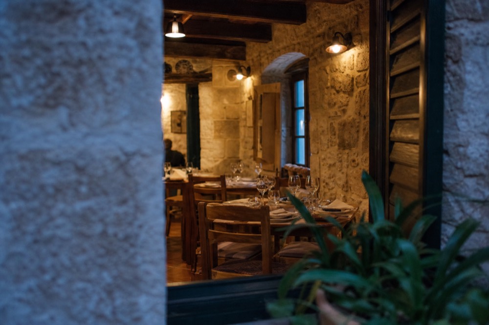 A small konoba dining room with stone walls and wooden tables set for dinner