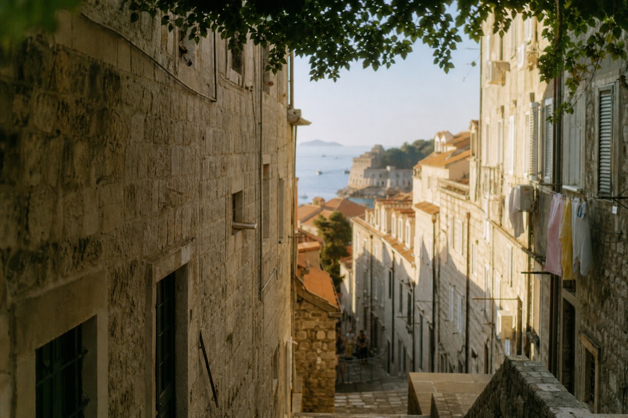 Sunlit limestone street inside Dubrovnik Old Town with stone buildings on both sides