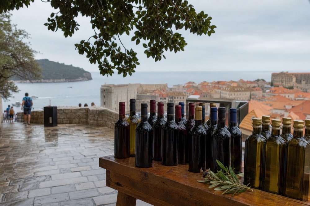 Bottles of local red wine and olive oil lined up on a wooden market table