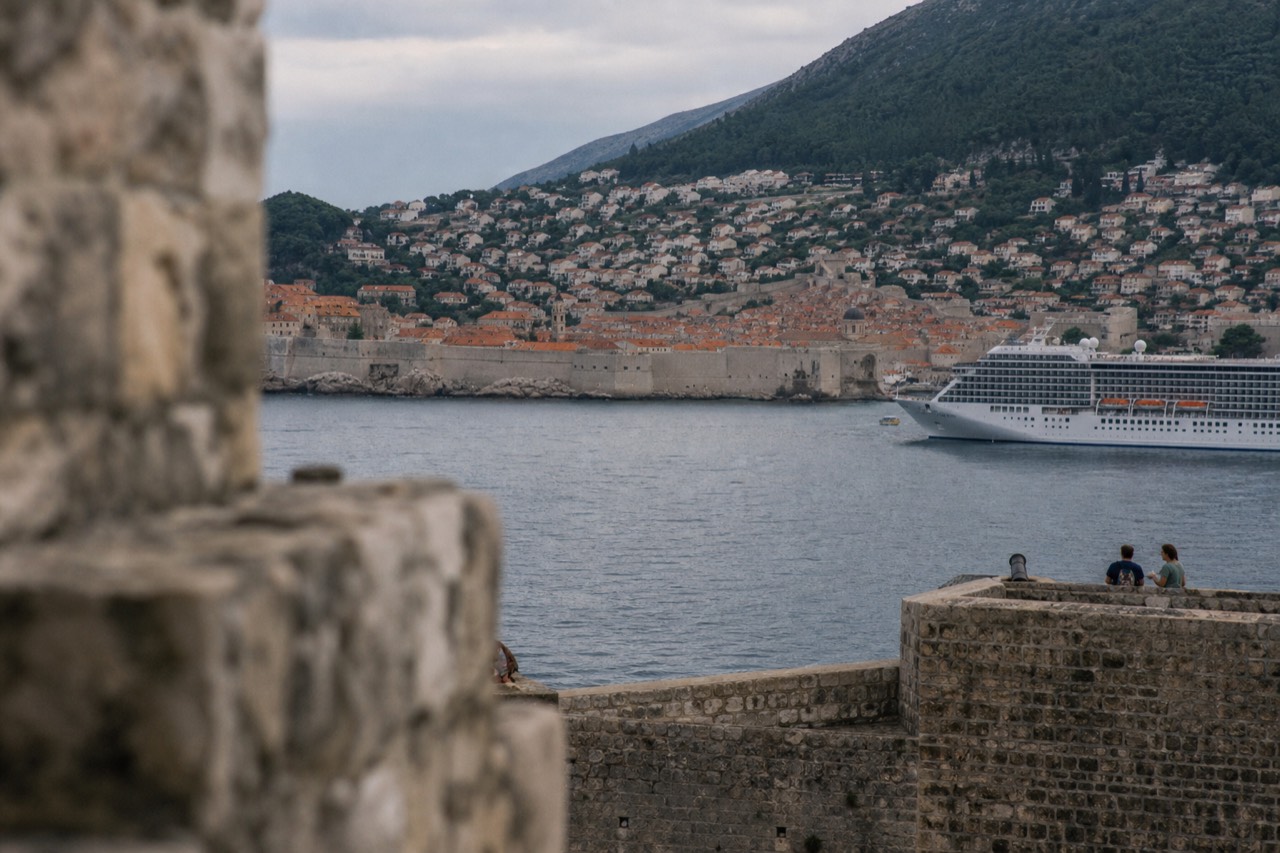 The walled Old Town of Dubrovnik seen from the Adriatic with terracotta rooftops and a cruise ship anchored offshore