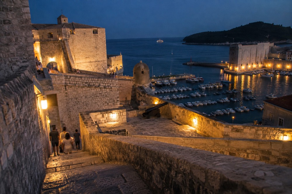 Illuminated stone fortress terrace above the old harbour at night