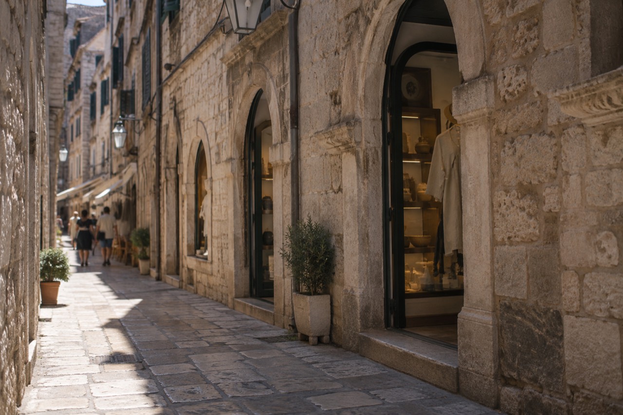 Shop fronts with stone arches along a narrow limestone street in Dubrovnik Old Town