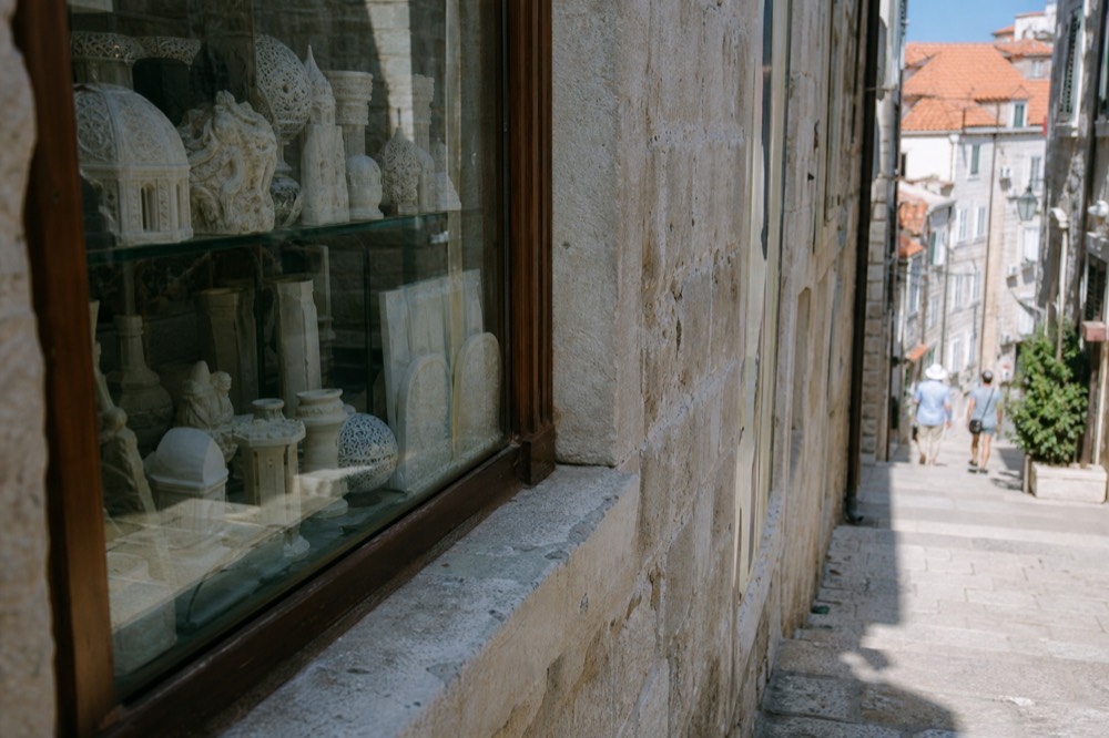 A shop window displaying hand-carved white stone souvenirs on a narrow Dubrovnik lane