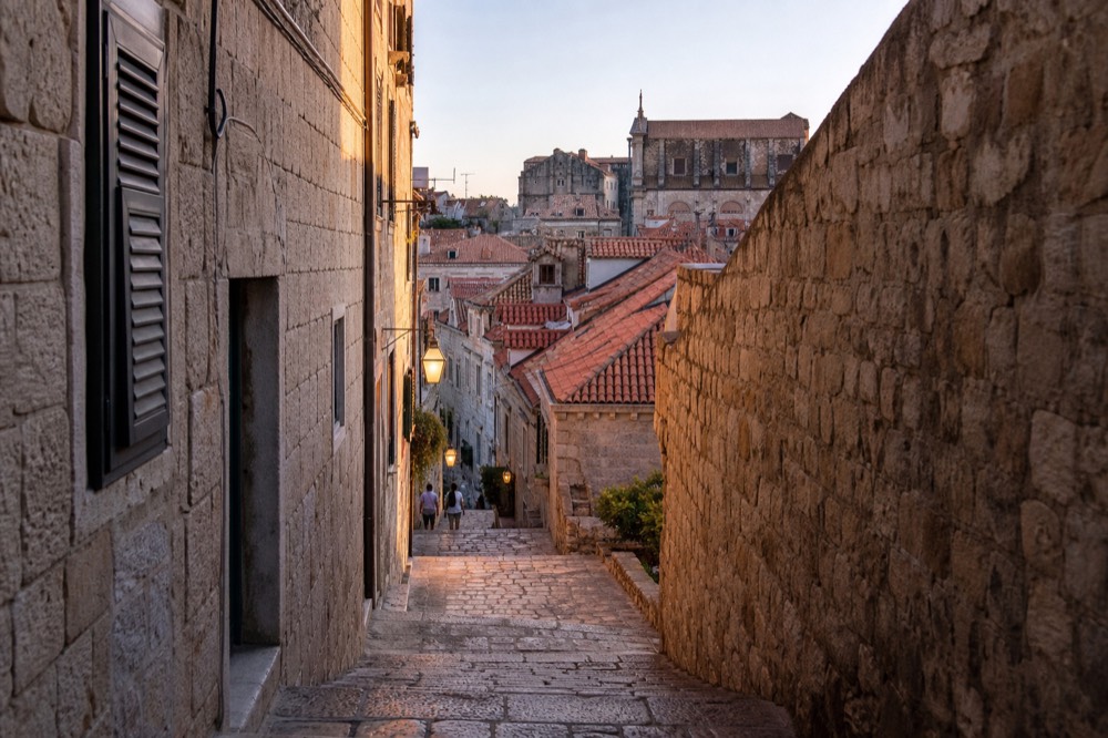 Narrow stone lane in Dubrovnik Old Town at dusk with warm light on the walls