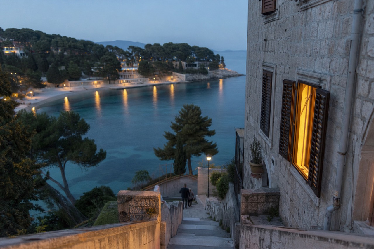 A calm swimming bay with clear water and a tree-lined promenade in Dubrovnik