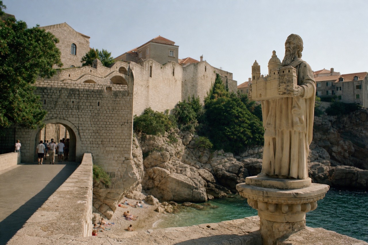 Stone statue of a saint holding a model of a walled city above an old Dubrovnik gateway