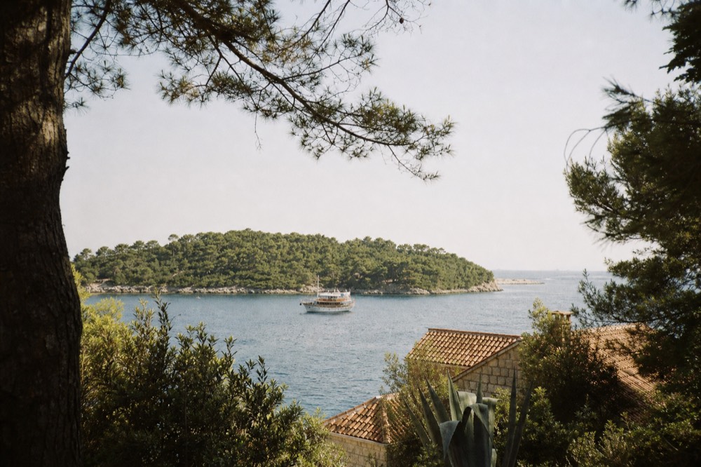 Boat anchored at a green island bay on the Elaphite cruise route