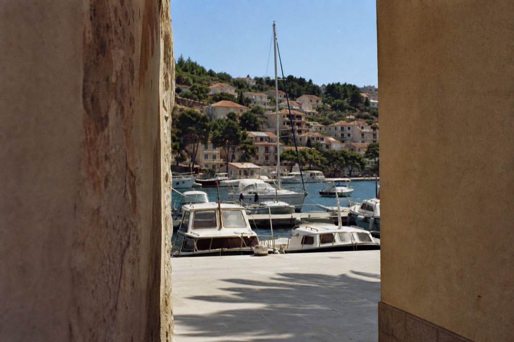 Fishing boats and small yachts moored in Gruž harbour with residential buildings on the hillside