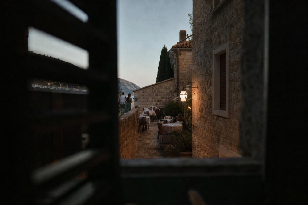 A small konoba terrace with tables set beside a stone lane near Pile