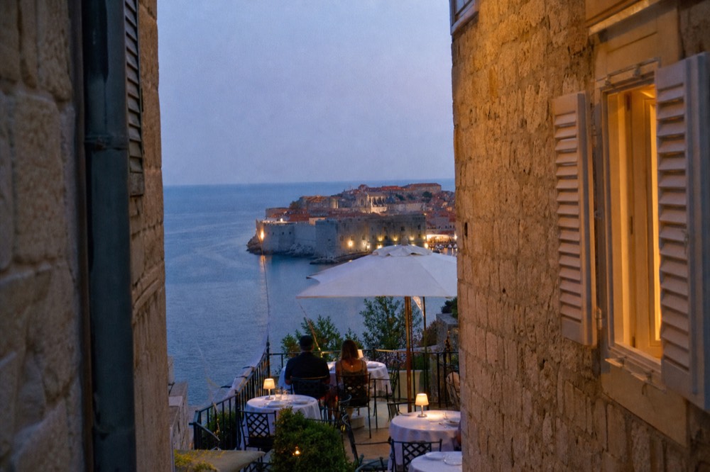 Hotel terrace in Ploče with white table settings overlooking the walled city at golden hour
