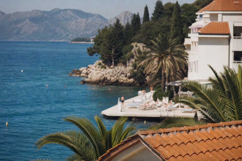 Modern resort hotel with palm trees and sun loungers beside the sea