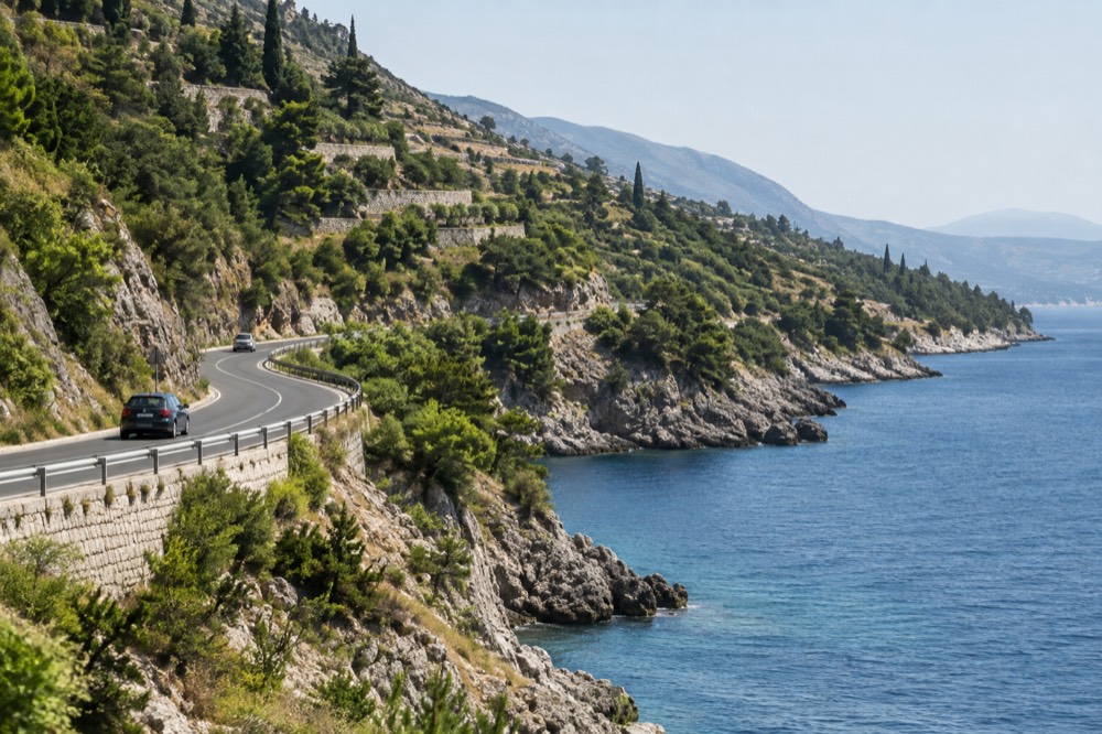 A road winding along a coastline with terraced hillsides sloping toward the sea