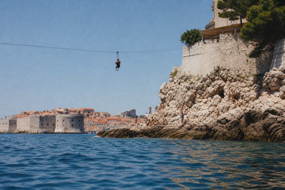 A person on the zipline with the Dubrovnik Old Town and the Adriatic Sea in the background