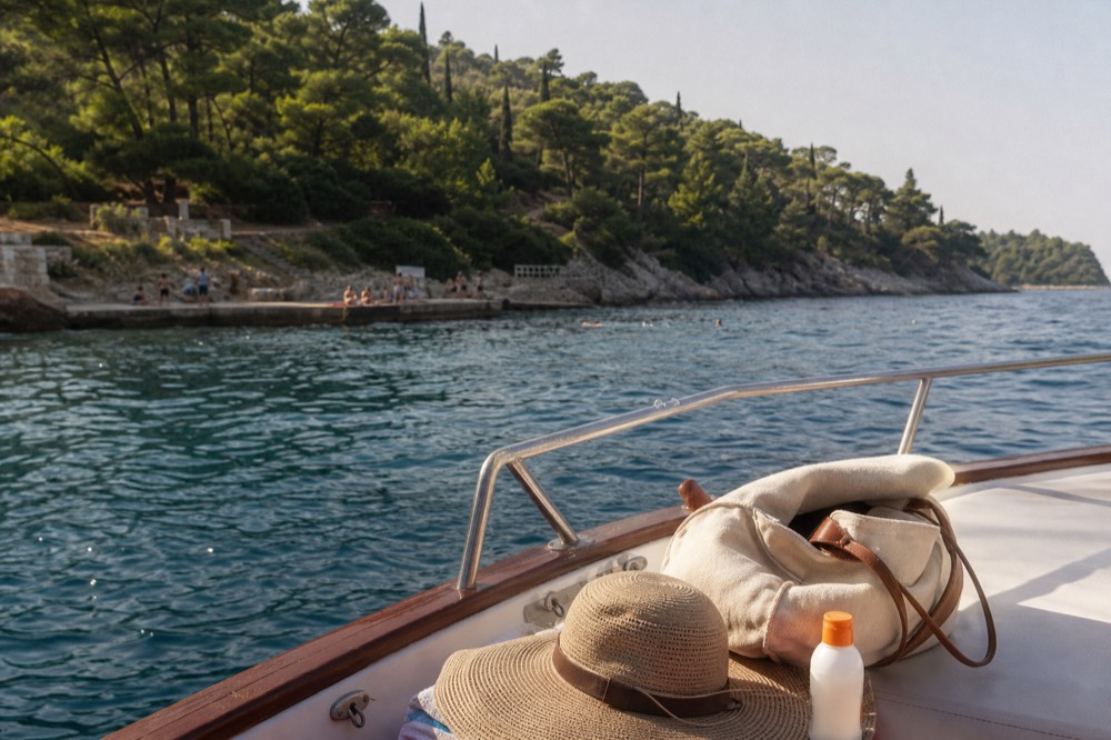 A bag, hat and sunscreen on a boat deck beside a rail