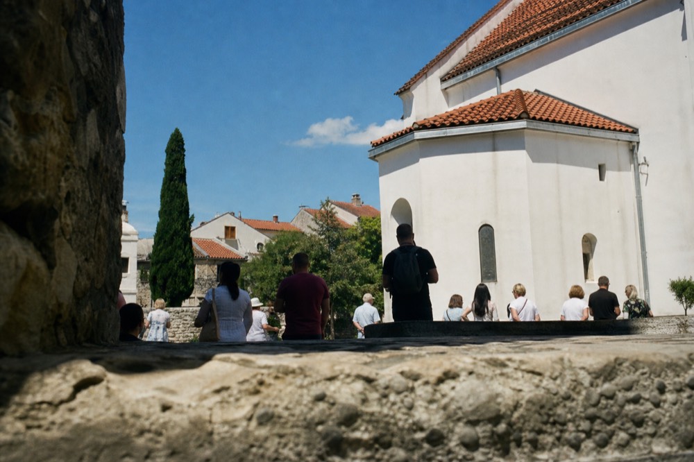 A church exterior with pilgrims gathered on a warm afternoon