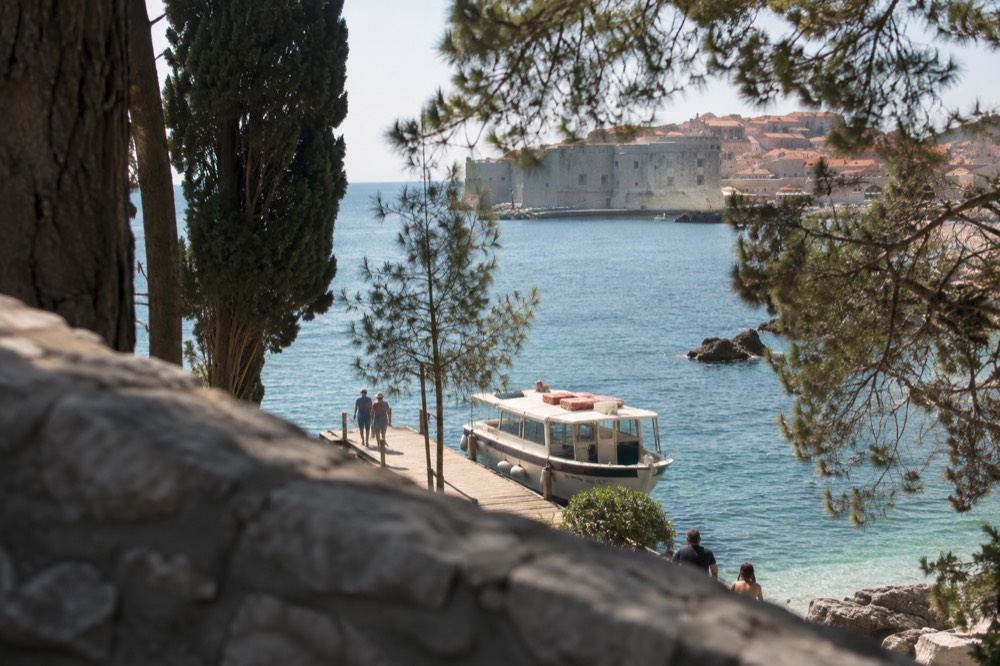 Small ferry boat at a wooden jetty beside clear blue Adriatic water