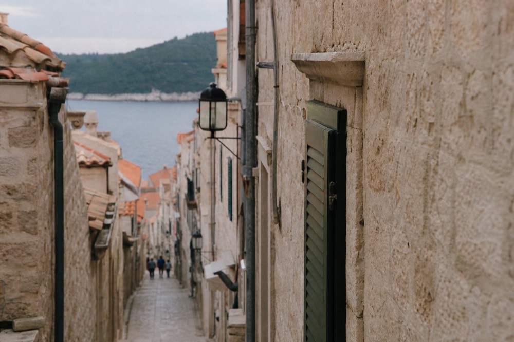 A narrow limestone street inside Dubrovnik Old Town with no vehicles, lined with stone buildings