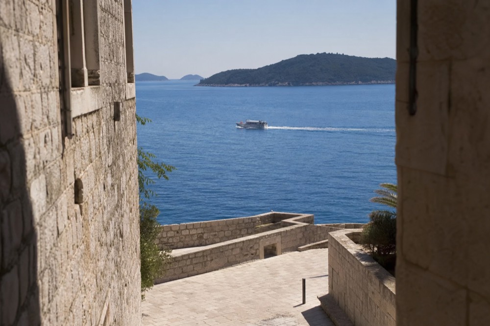A boat crossing open blue water toward green islands on the horizon near Dubrovnik