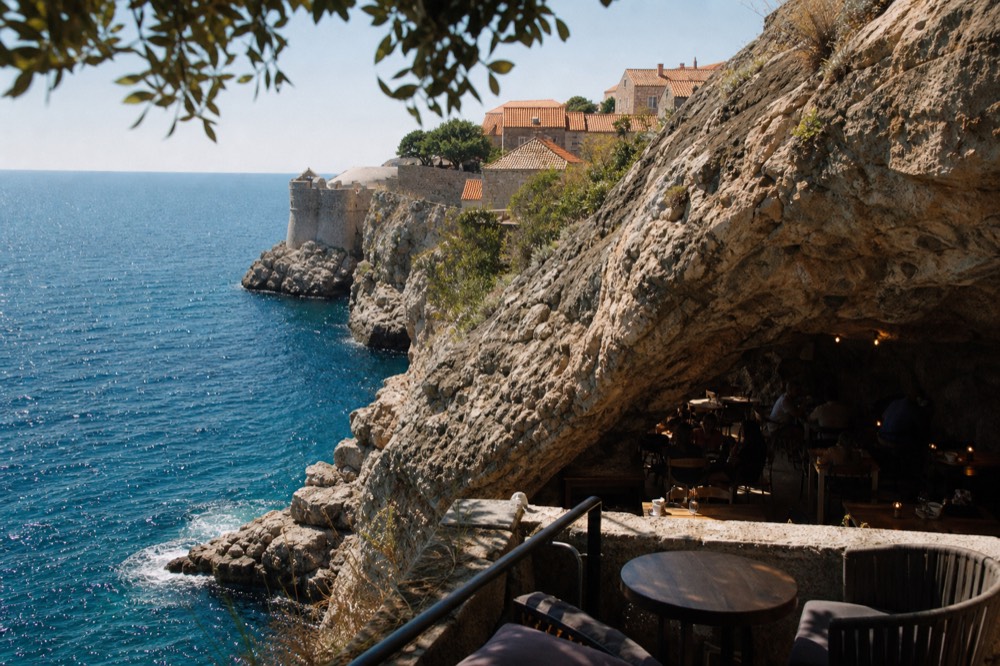 Tables and soft lighting inside a natural limestone cave bar beside the sea