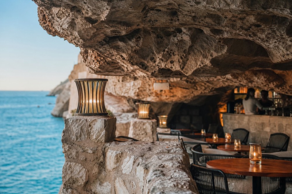 A cave bar interior with a carved stone ceiling and warmly lit tables