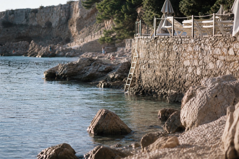 A calm swimming cove with clear water beside a stone terrace in the evening