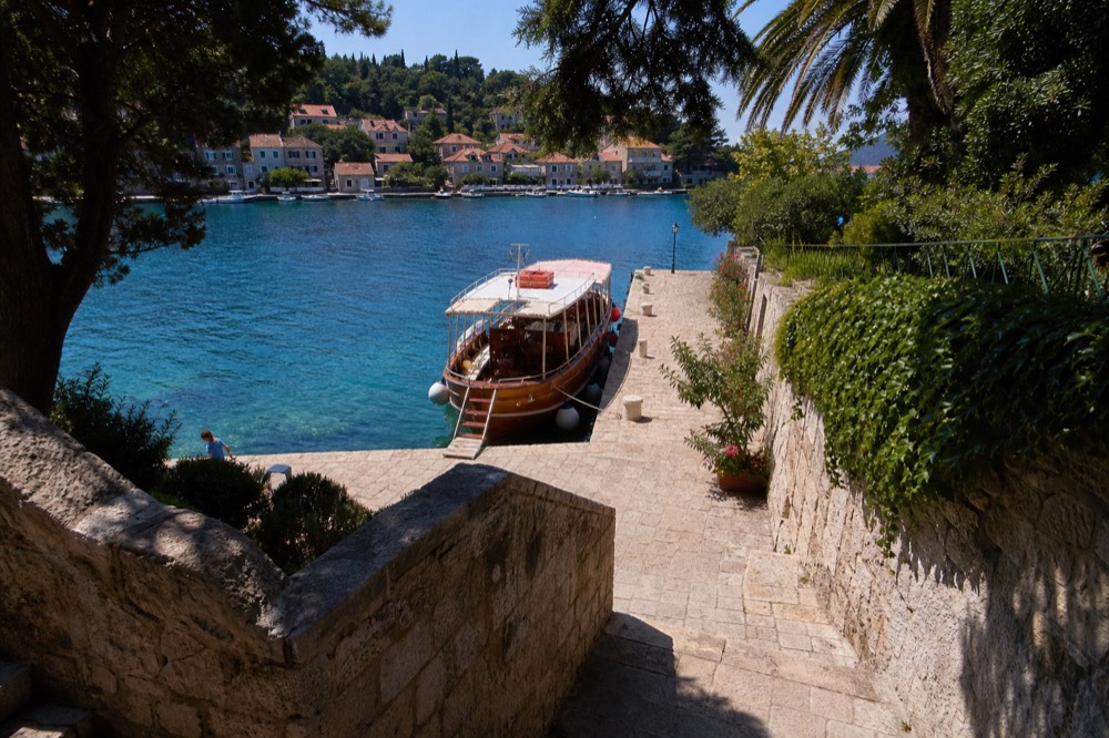 Wooden tourist boat moored at a small stone quay beside clear turquoise water