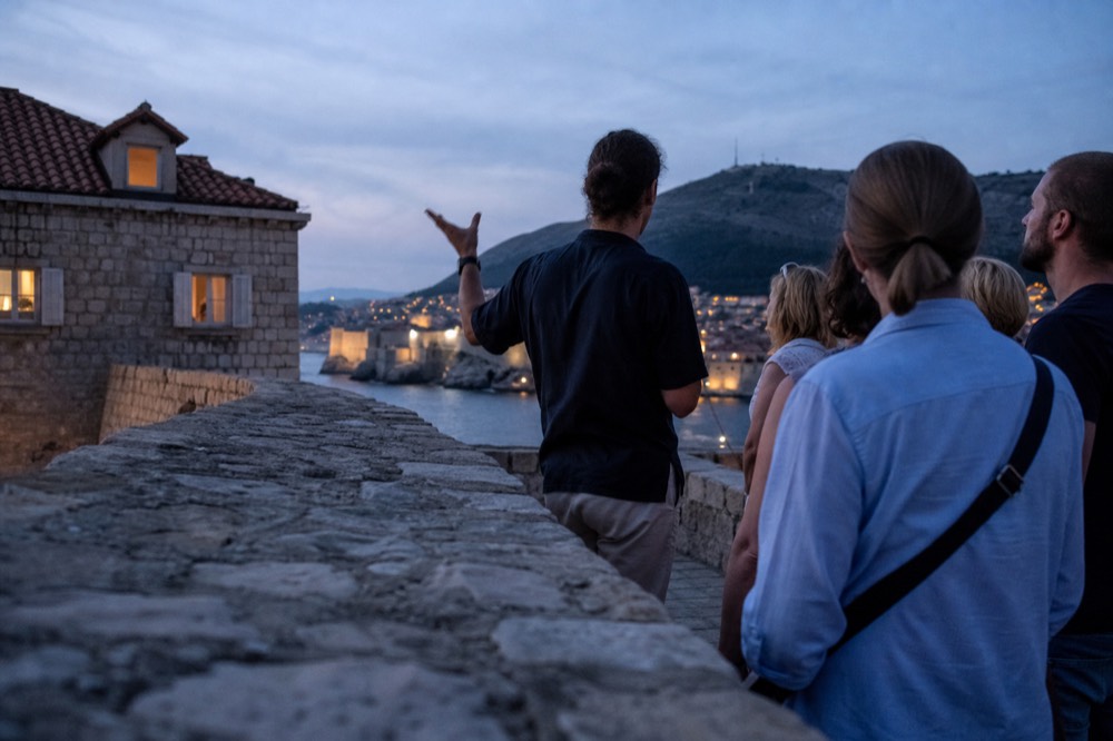Guide speaking to a small group on the ramparts above the harbour