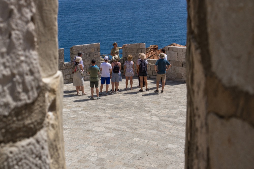 Guide speaking to a small group beside a crenellated wall parapet