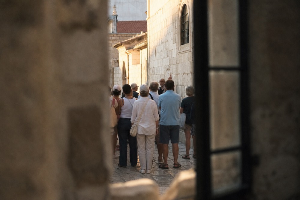 Guided walking group listening to a guide on a stone street in the Old Town