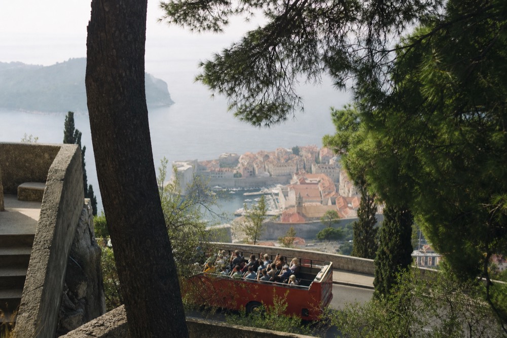 Convertible bus tour passing the Old Town with passengers taking photos