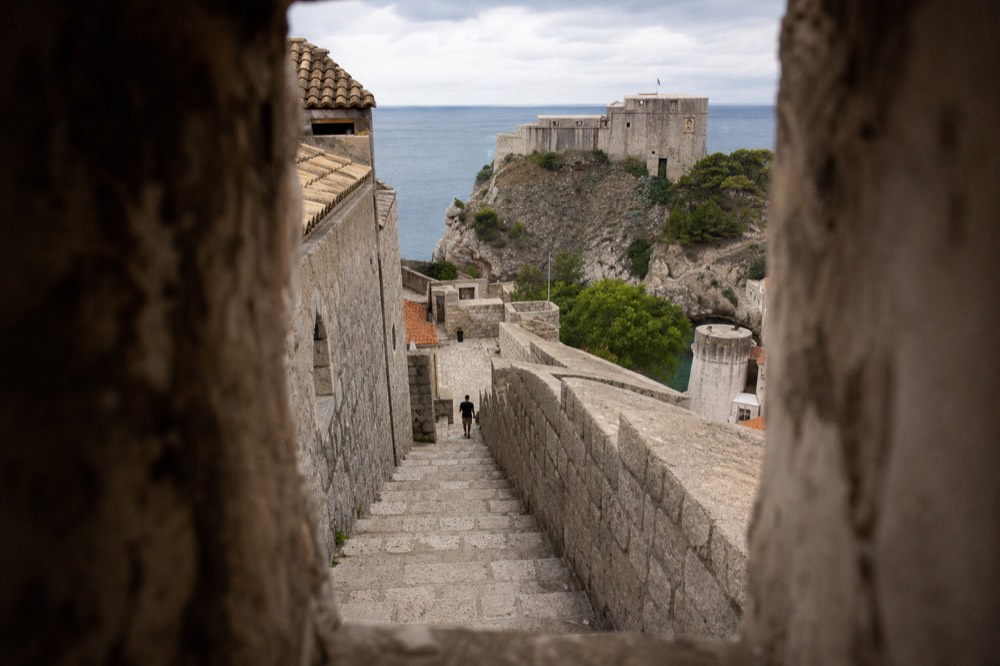 Stone stairway climbing between towers on the Dubrovnik city walls with sea beyond
