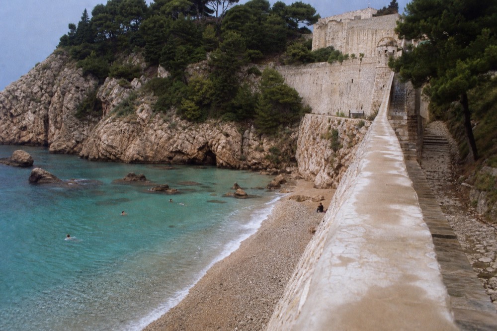 Clear turquoise water at a pebble beach near Dubrovnik with swimmers