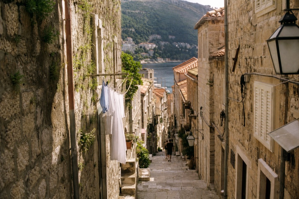 Stone staircase alley in Dubrovnik Old Town with laundry lines and warm afternoon light
