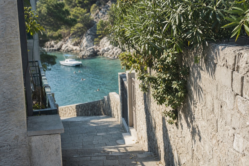 Small open boat anchored in a quiet cove with swimmers near the shore