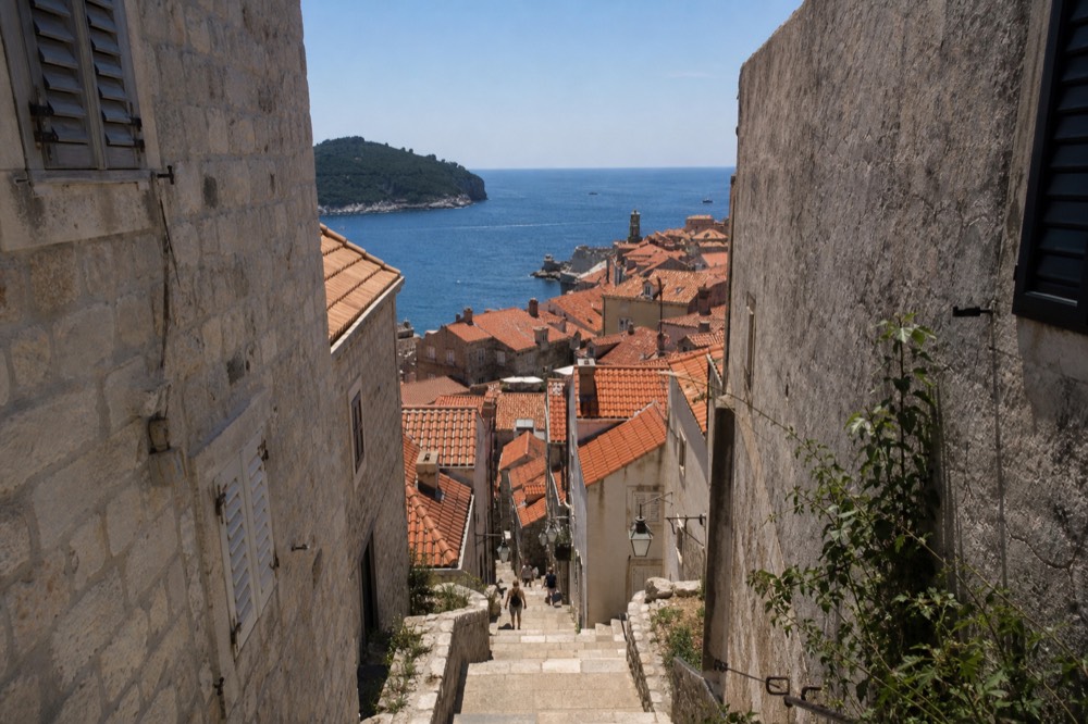 Sunlit limestone buildings and shutters in Dubrovnik under a clear blue sky