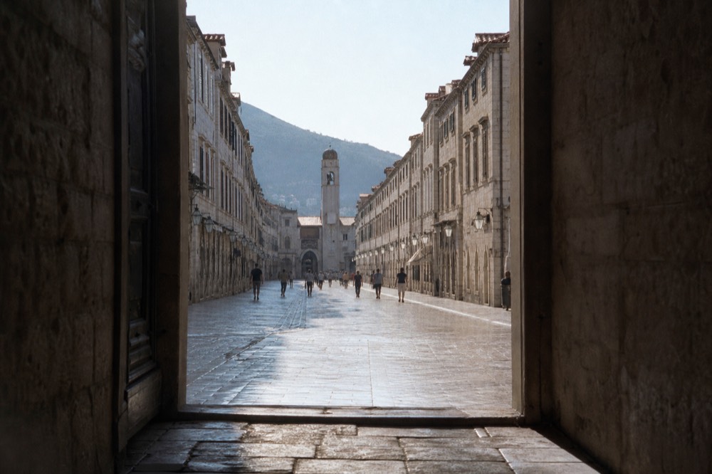 A stone-paved main street lined with uniform baroque buildings in an old Adriatic town
