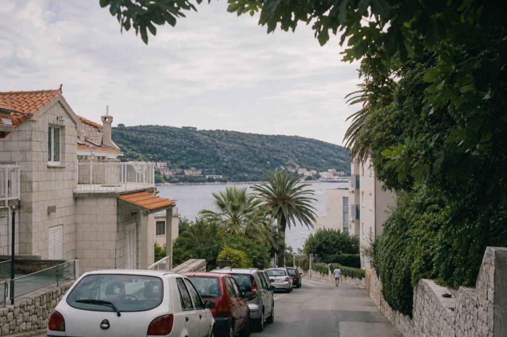 A quiet residential street in Lapad with palm trees and apartment buildings near the seafront